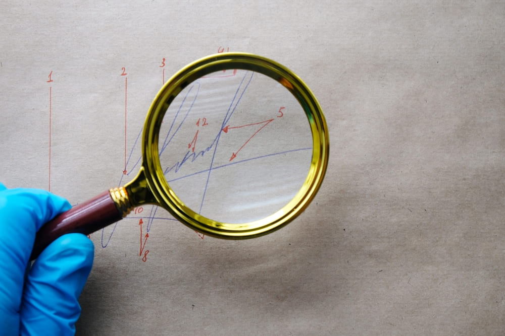 A hand writing expert looking at a signature with a magnifying glass